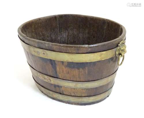 A 19thC coopered oak and brass banded ice bucket / wine cooler with twin lion mask ring handles.