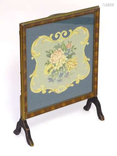 A 20thC fire screen with a moulded surround above a glazed needlework centre. 22