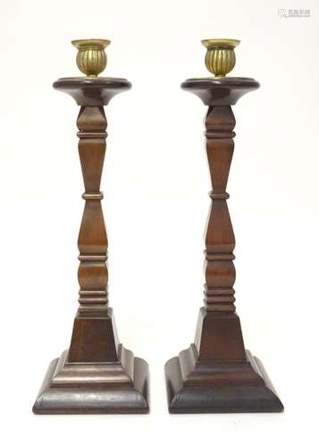 A pair of early 20thC carved wooden candlesticks of squared form with brass sconces. Approx. 14