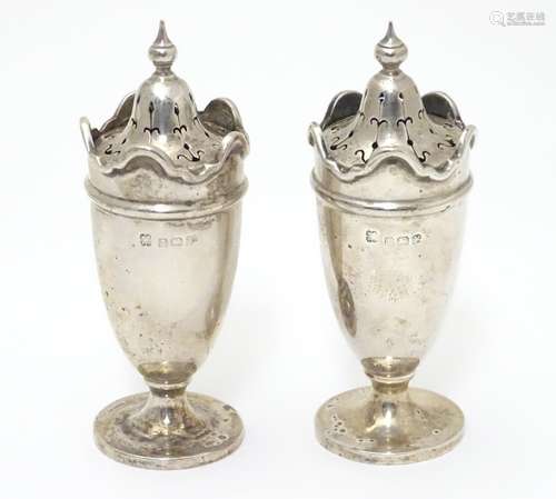 A pair of silver pepperettes with wavy-edged rims. Hallmarked Birmingham 1923 maker Martin Hall & Co