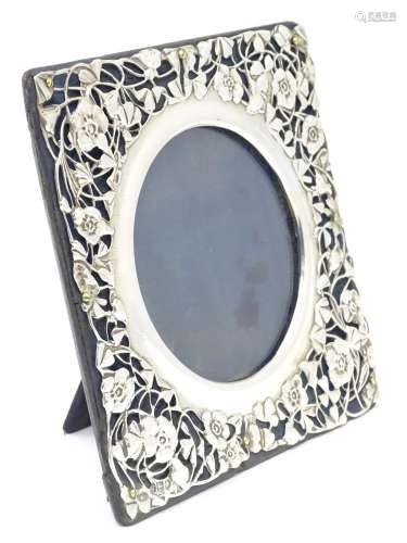 A photograph frame with Art Nouveau silver surround with floral and foliate detail. hallmarked