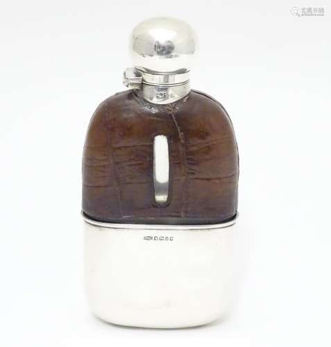 A Victorian glass hip flask with half leather covering, silver beaker lower and silver mounts.
