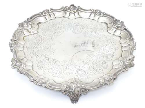 A Victorian silver salver with engraved decoration and on three scrolled feet. Hallmarked London