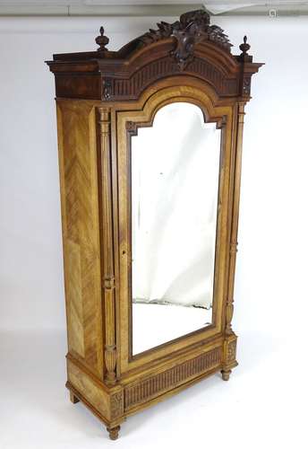 A late 19thC rosewood armoire with a shaped carved pediment flanked by turned finials and having a