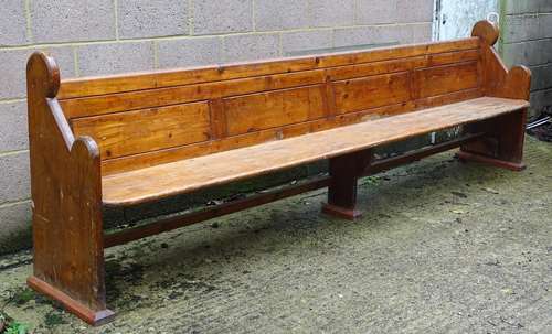 A mid / late 19thC pine pew with scrolled ends, panelled back and full length stretcher. 132