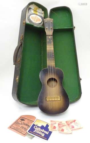 Musical Instrument: a mid 20thC Ukelele, in sunburst finish with case, sheet music and strings.