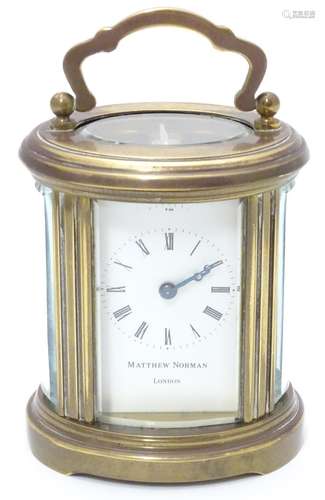 A late 20th Century small carriage clock by Matthew Norman , London. With oval brass case, the white