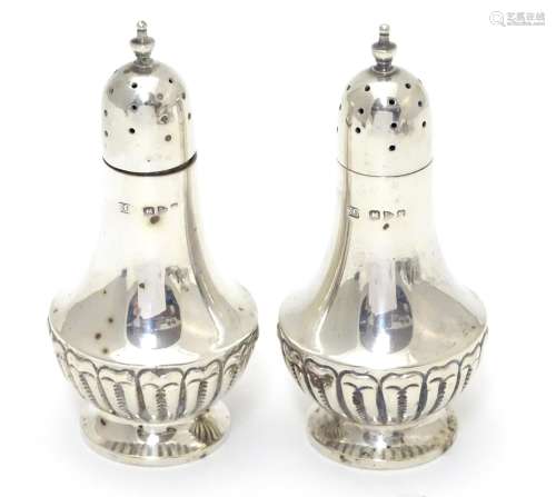 A pair of silver pepperettes with fluted decoration. Hallmarked Chester 1900, maker Colen Hewer