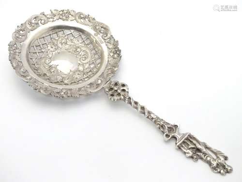 An ornate silver strainer / sifter spoon with figural detail to handle and floral and acanthus