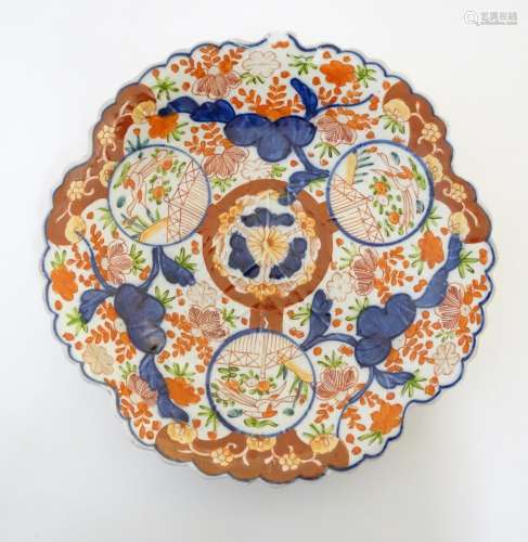 A Japanese Imari plate with a scalloped rim with stylised leaf veins in relief to the centre,