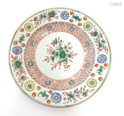 A Chinese plate with central floral and foliate detail, with a patterned border with flowers and