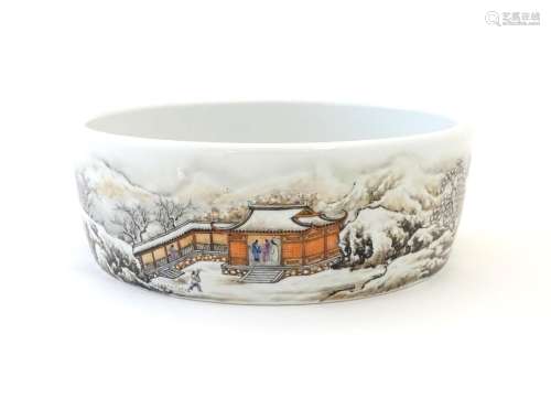 A Chinese circular dish with hand painted decoration depicting a winter snowy landscape scene with