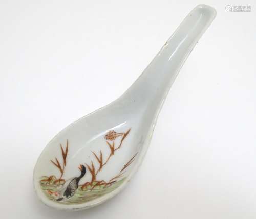 A Chinese soup spoon with hand painted decoration depicting a goose / bird in a wetland landscape.