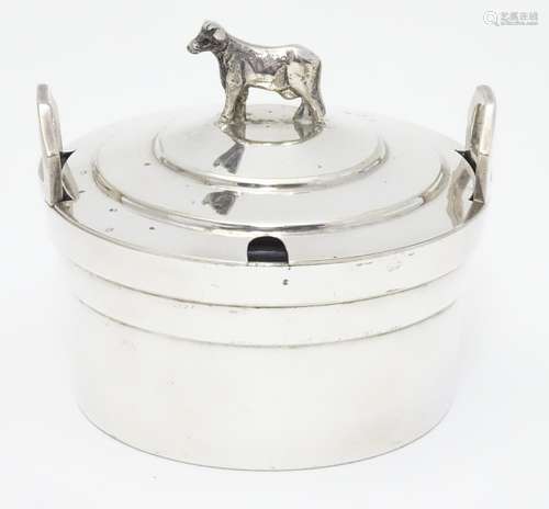 A silver plate butter dish of circular form with glass liner, the lid with cow formed finial. 4