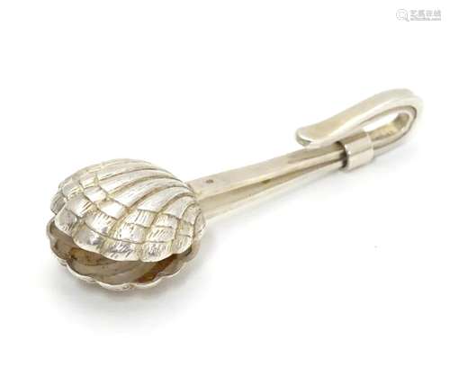 A white metal napkin clip with scallop shell formed grips. 2