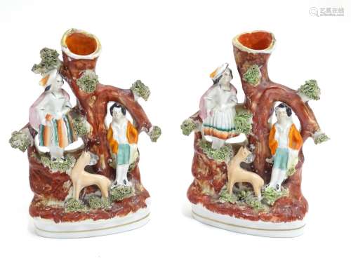 A pair of Staffordshire figural spill vases with a man and woman resting on the branches of a tree