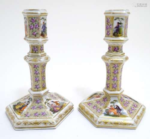 A pair of Berlin porcelain candlesticks on hexagonal bases with gilt and floral detail and hand