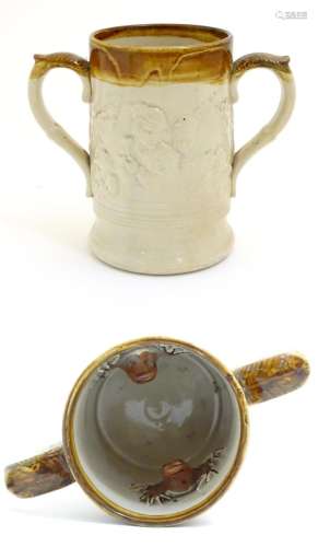A 19thC two tone stoneware loving cup tankard, the body moulded in relief with tavern scenes with