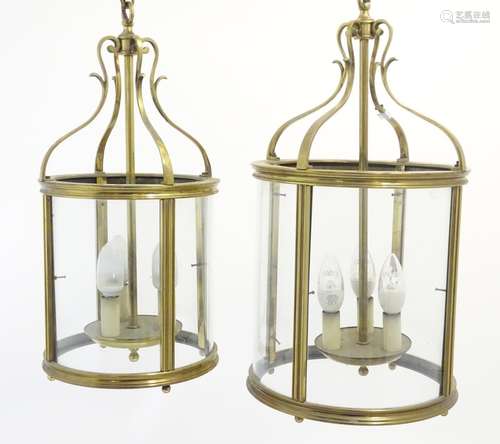 Two brass pendant hall lights of lantern form each with four glass panels. The largest aprox 23