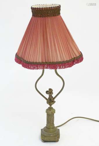 A mid to late 20thC brass table lamp, formed as a Corinthian column surmounted by a putto. 22