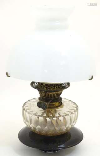 A 19thC oil lamp, the black glass base with facet cut glass reservoir and white milk glass shade.