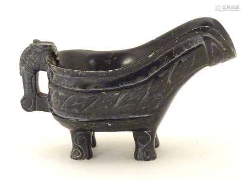 An Oriental carved stone vessel with a pouring spout, beast formed handle and four feet. The side