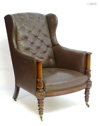 A mid 19thC wingback leather armchair with a deep buttoned backrest, two turned supports above