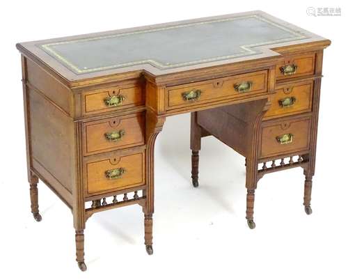 An early 20thC writing table with a gold tooled leather top above a central drawer flanked by two