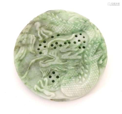 An Oriental jade roundel carving depicting a stylised dragon. Approx. 2 1/4