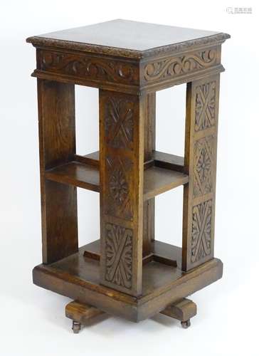 An early 20thC oak revolving bookcase with a moulded squared top above a lozenge carved floral frame