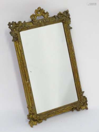 A late 19thC / early 20thC mirror with a giltwood and gesso frame having carved and moulded