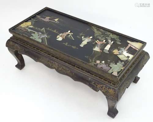 An oriental coffee table with a glass top, the table top depicting figures and scenes, most of the