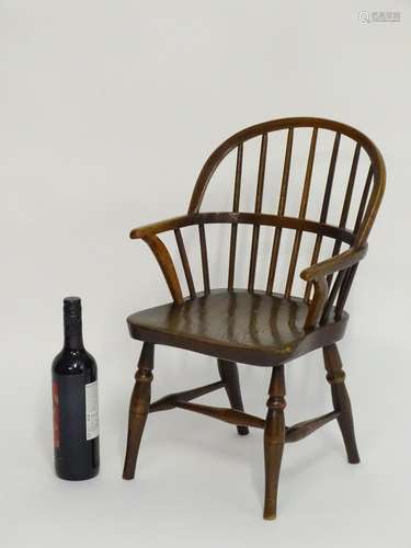 A mid 19thC childs Windsor chair with a double bow back above an elm seat and turned tapering legs