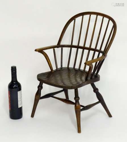 A mid 19thC childs Windsor chair with a double bow back above swept arms an elm seat and standing on