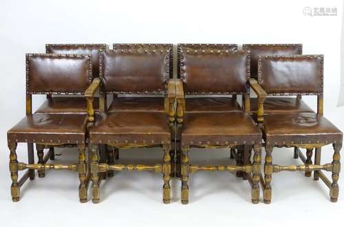 A set of eight mid 20thC dining chairs with leather and brass studded upholstery, standing on