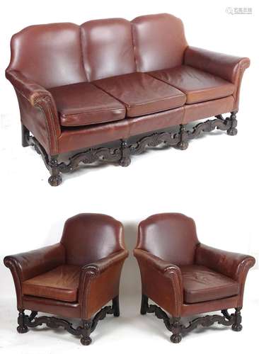 An early 20thC three piece leather suite with scrolled arms and carved legs united by shaped