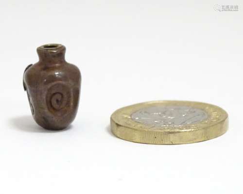 A Japanese ojime bead formed as a stylised vase with impressed detail and applied brass character