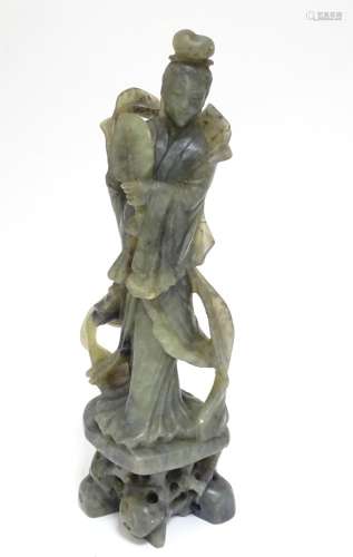 An Oriental carved soapstone figure of a lady holding a fan, wearing flowing robes, on a carved