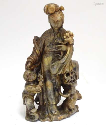A Chinese carved soapstone figural group modelled as Guanyin and a child, the goddess holding a