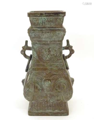 An Oriental cast bronze vase with twin mask handles with a looped ring, the body decorated with