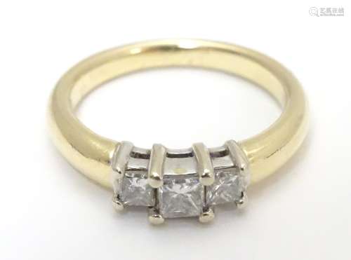 A 14kt gold ring set with trio of diamonds. The central diamond approx. 1/8