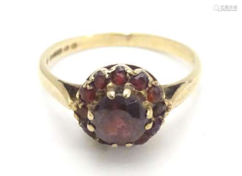 A 9ct gold ring set with garnet cluster ring, the central stone surrounded by twelve smaller stones.