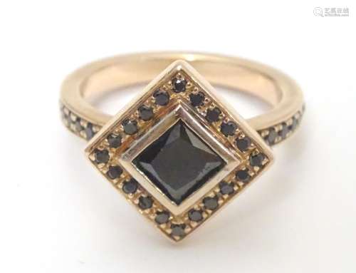 A 14ct rose gold ring set with central princess cut black diamond bordered by round brilliant cut
