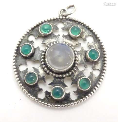 An Arts & Crafts white metal pendant set with central moonstone cabochon bordered by green stone