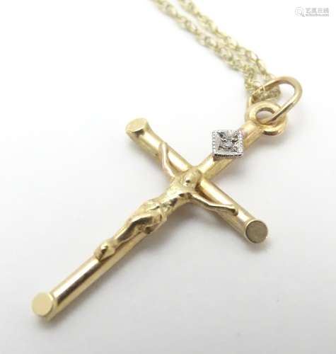 A 9ct gold pendant formed as a crucifix set with single diamond on a 18