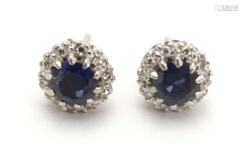 A pair of 9ct white gold stud earrings set with central blue spinel bordered by white stones in a