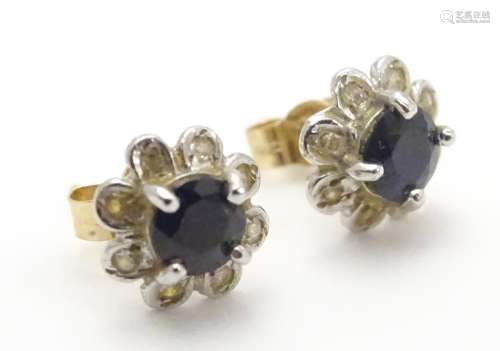 A pair of 9ct gold stud earrings set with central blue stone bordered by chip set diamonds.
