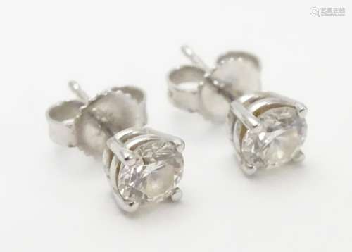 A pair of white gold stud earrings set with diamond solitaires. The diamond approximately 1/8