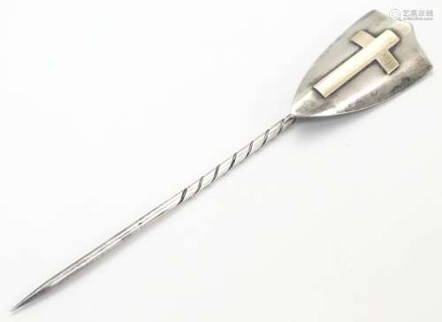 A hallmarked silver stick pin surmounted by a shield cartouche with cross decoration. The whole