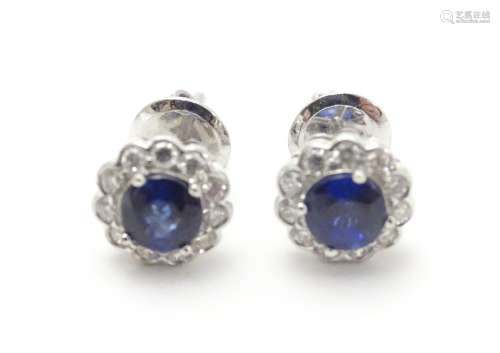 A pair of 18ct gold stud earrings set with central sapphire bordered by diamonds. Approx. 1/4
